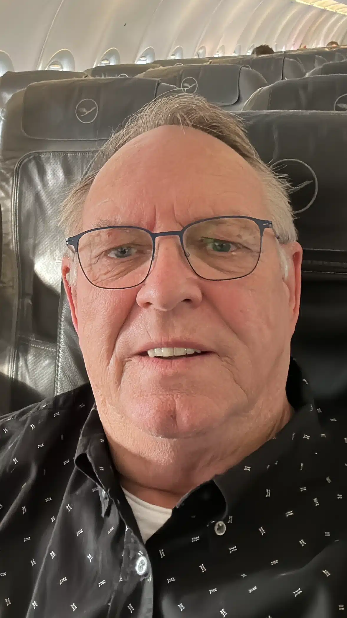 Hans-Jürgen Göbel als lächelnder Mann mit Brille im Lufthansa Flieger