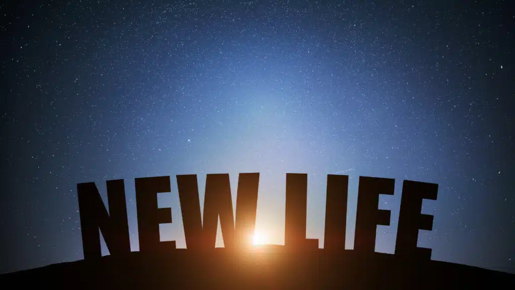 Schriftzug New Life vor Sternenhimmel und Sonnenaufgang als Symbol für einen Neustart im Leben mit 50