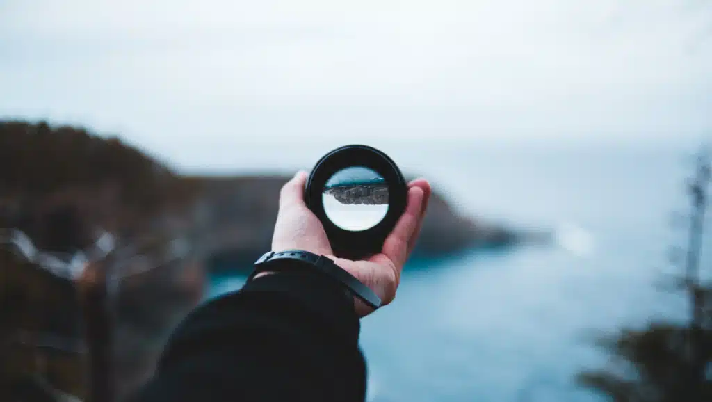 Hand hält Linse mit Blick auf Landschaft als Symbol für Perspektivwechsel und Neustart im Leben mit 50