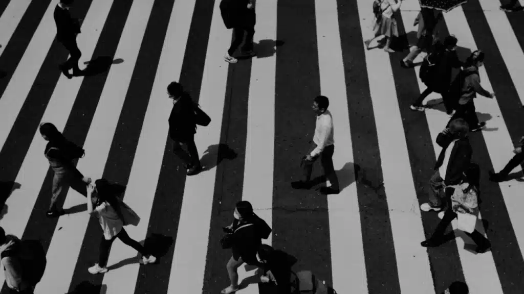 Menschen überqueren Zebrastreifen als Symbol für Orientierung im Leben und Entscheidungen während der Midlife-Crisis bei Männern